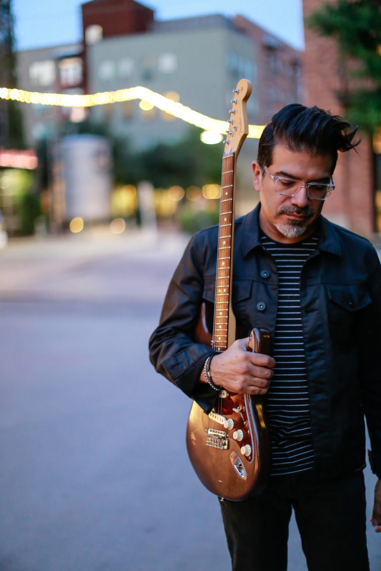 Photo of Adam Zuniga holding a guitar